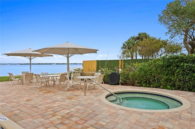 view of swimming pool featuring a community hot tub, a patio, and a water view