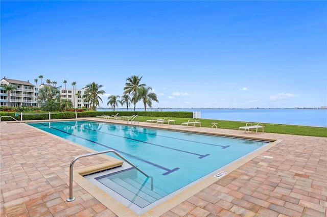 view of pool featuring a water view, a yard, and a patio area