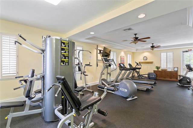 exercise room with a textured ceiling, ceiling fan, crown molding, and a tray ceiling