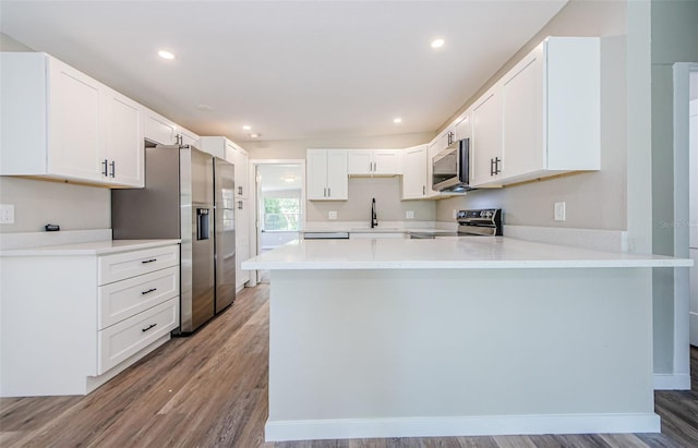 kitchen featuring white cabinetry, kitchen peninsula, stainless steel appliances, and light hardwood / wood-style floors