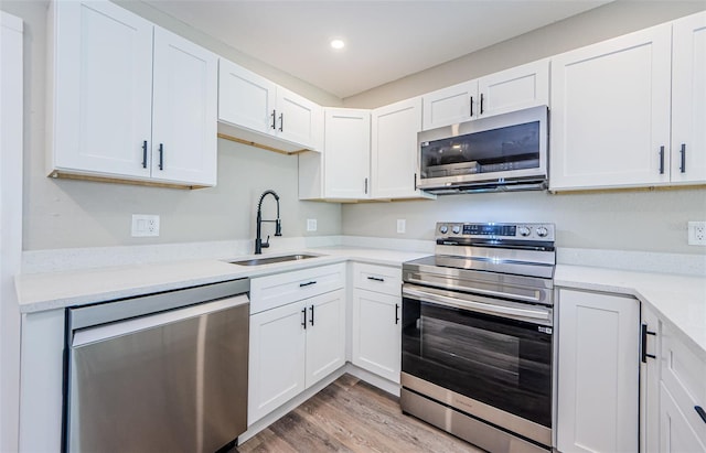 kitchen with stainless steel appliances, light hardwood / wood-style floors, white cabinets, and sink