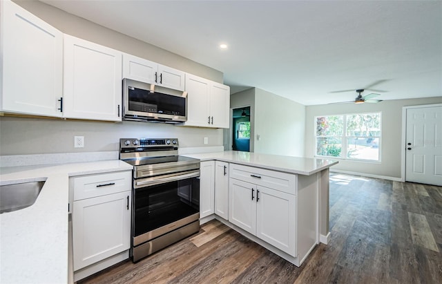 kitchen with stainless steel appliances, kitchen peninsula, dark hardwood / wood-style floors, ceiling fan, and white cabinetry