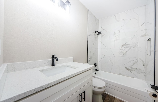 full bathroom with tiled shower / bath, vanity, hardwood / wood-style floors, and toilet