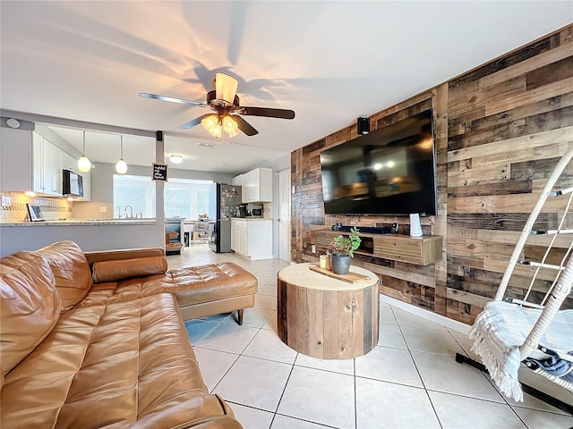 tiled living room featuring sink, ceiling fan, and wooden walls