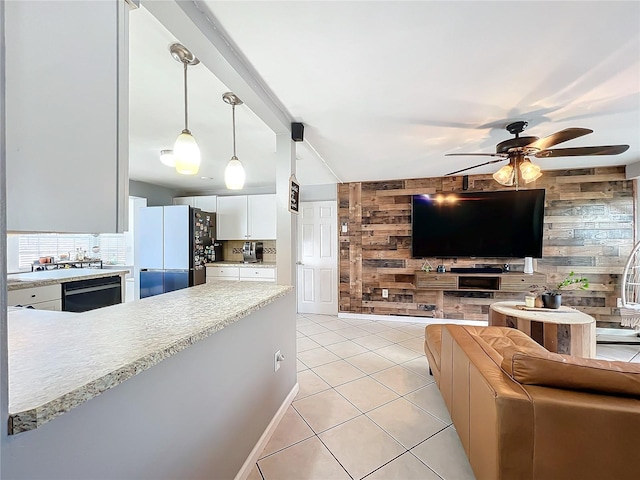 kitchen with pendant lighting, white cabinetry, wood walls, and fridge