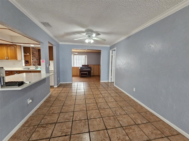 kitchen featuring ceiling fan, a textured ceiling, sink, and crown molding