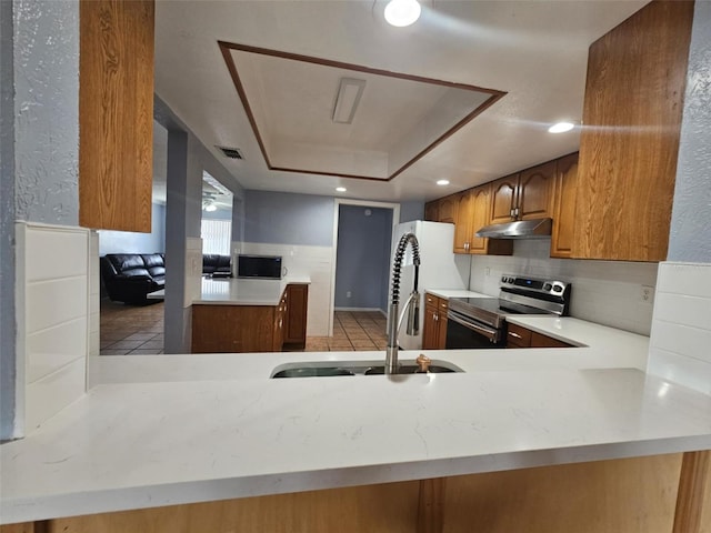 kitchen featuring sink, a tray ceiling, kitchen peninsula, and electric stove