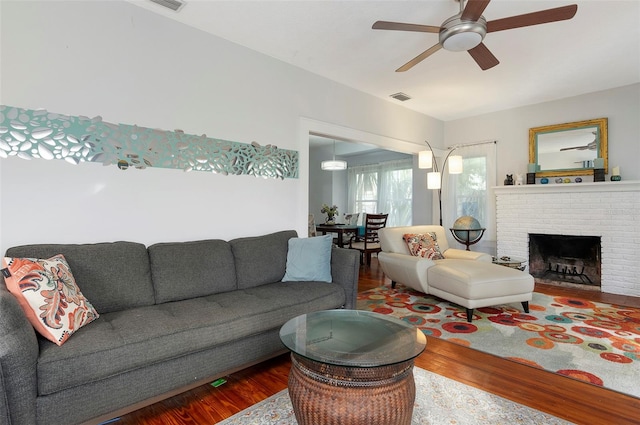 living room with a fireplace, wood-type flooring, and ceiling fan