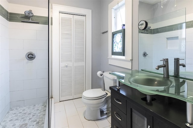 bathroom with tile patterned flooring, vanity, toilet, and tiled shower