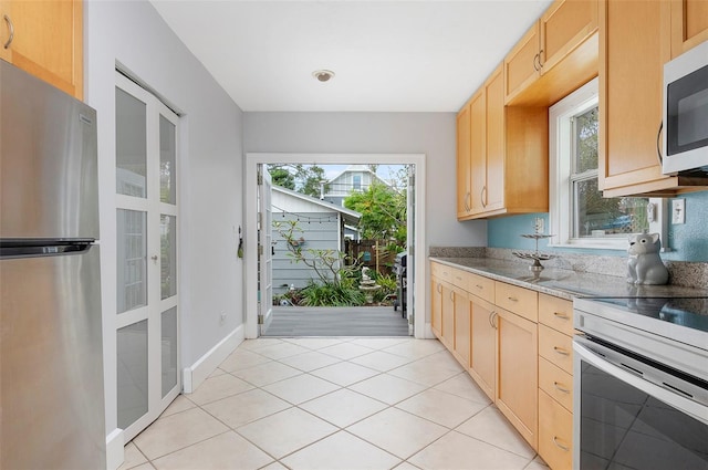 kitchen featuring light brown cabinetry, white appliances, light stone counters, and light tile patterned floors