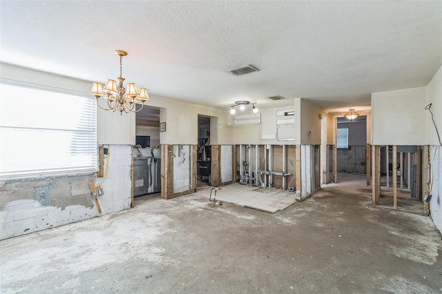 interior space with concrete floors, an inviting chandelier, and a textured ceiling