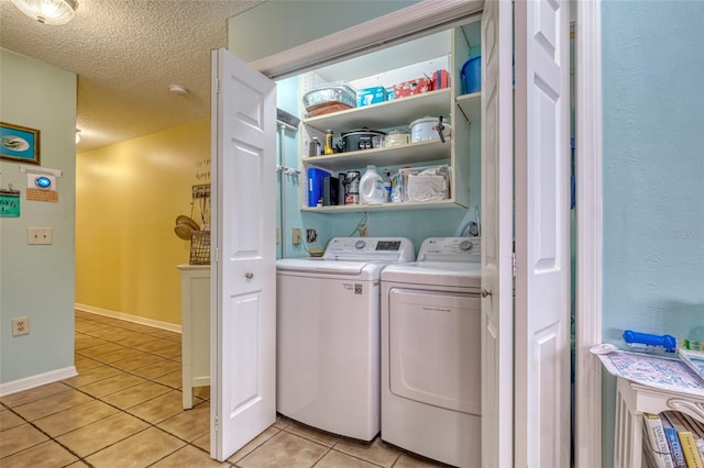 laundry area featuring independent washer and dryer, light tile patterned flooring, and a textured ceiling