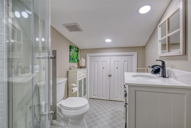 bathroom with a shower with door, vanity, toilet, and tile patterned floors