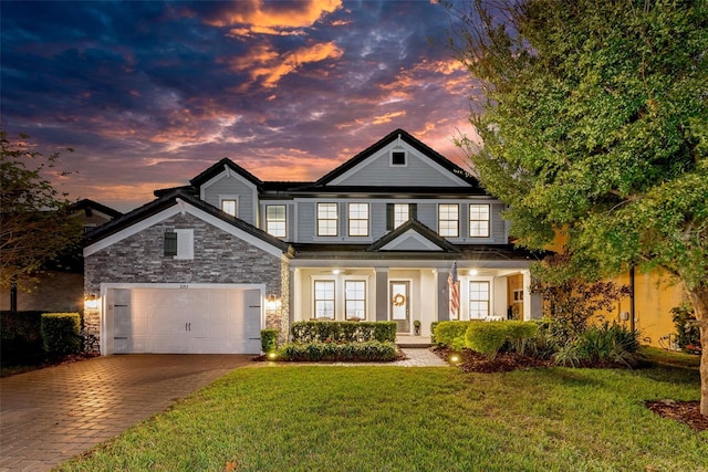 view of front of property featuring a garage, a yard, and covered porch