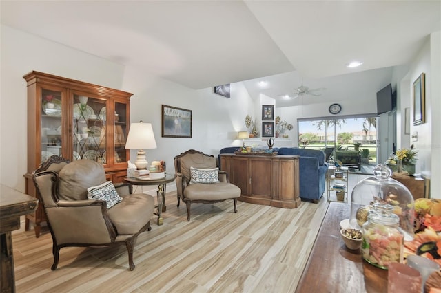 living room featuring ceiling fan, light hardwood / wood-style floors, and lofted ceiling