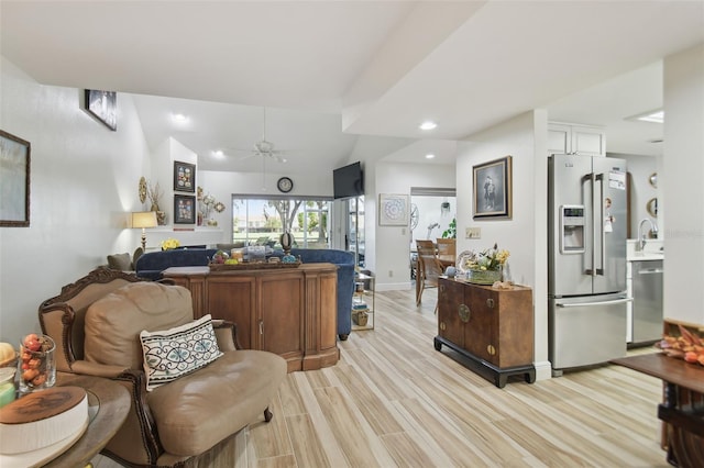 living room featuring ceiling fan, light wood-type flooring, sink, and lofted ceiling