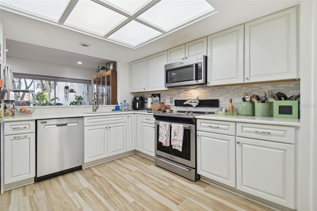 kitchen featuring light hardwood / wood-style floors, white cabinetry, stainless steel appliances, and tasteful backsplash