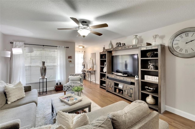 living room with a textured ceiling, light hardwood / wood-style floors, and ceiling fan