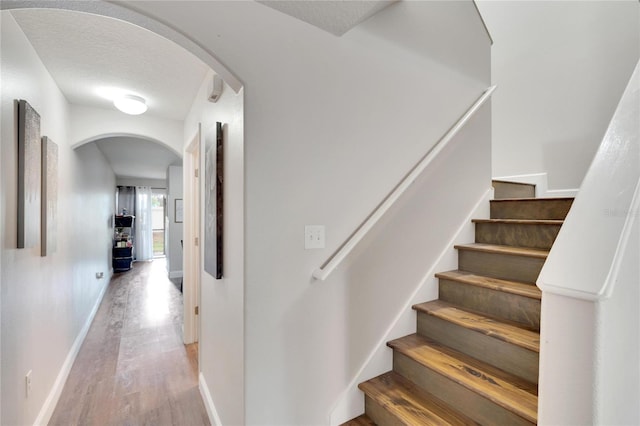 staircase with hardwood / wood-style floors and a textured ceiling