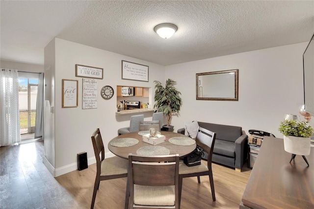 dining space featuring light hardwood / wood-style flooring and a textured ceiling