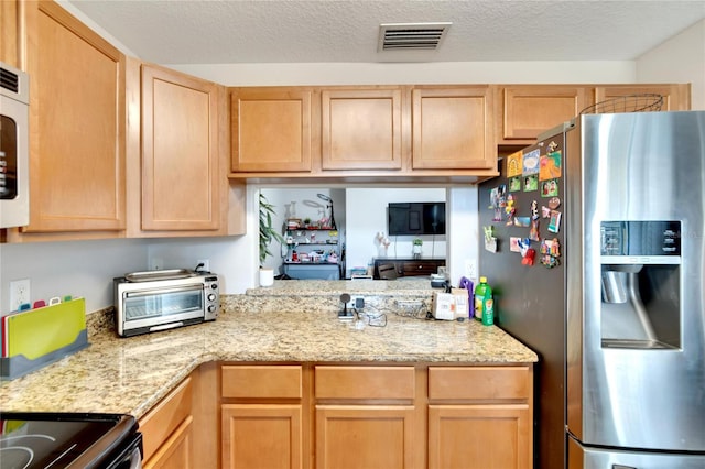 kitchen featuring appliances with stainless steel finishes, a textured ceiling, and light brown cabinets