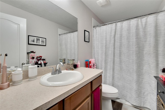 bathroom with a textured ceiling, vanity, and toilet