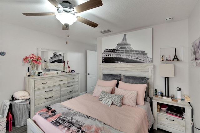 bedroom featuring ceiling fan, dark hardwood / wood-style flooring, and a textured ceiling