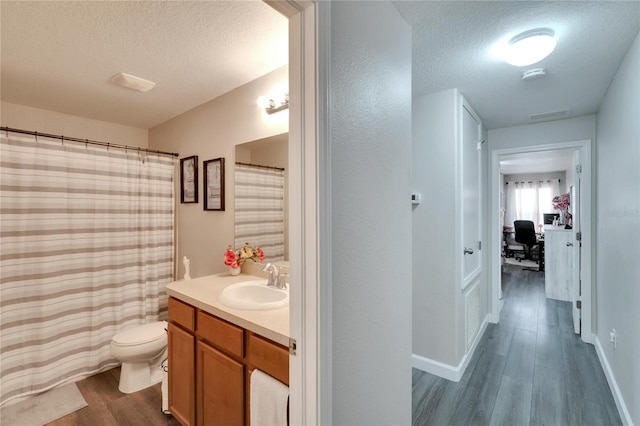 bathroom with a textured ceiling, vanity, hardwood / wood-style flooring, and toilet