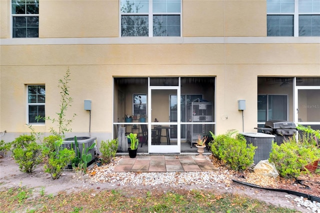 view of exterior entry with a patio and central AC