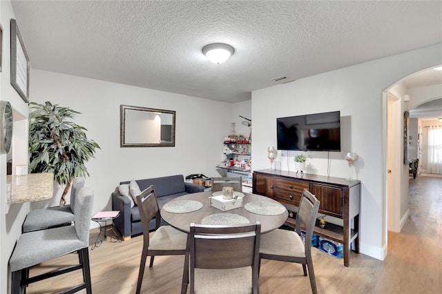 dining space featuring a textured ceiling and light hardwood / wood-style floors