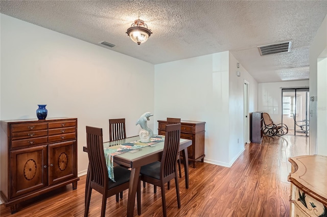 dining room featuring wood-type flooring and a textured ceiling