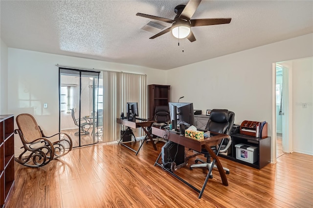 home office featuring a textured ceiling, hardwood / wood-style flooring, and ceiling fan