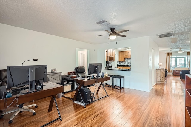 office with light hardwood / wood-style floors, ceiling fan, and a textured ceiling