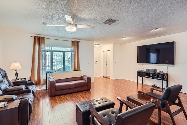 living room with hardwood / wood-style floors, ceiling fan, and a textured ceiling