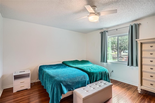 bedroom with ceiling fan, a textured ceiling, and dark hardwood / wood-style floors