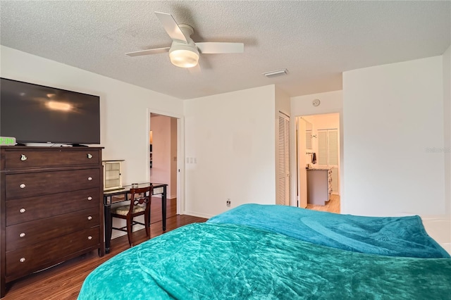 bedroom with hardwood / wood-style floors, a textured ceiling, ensuite bathroom, ceiling fan, and a closet