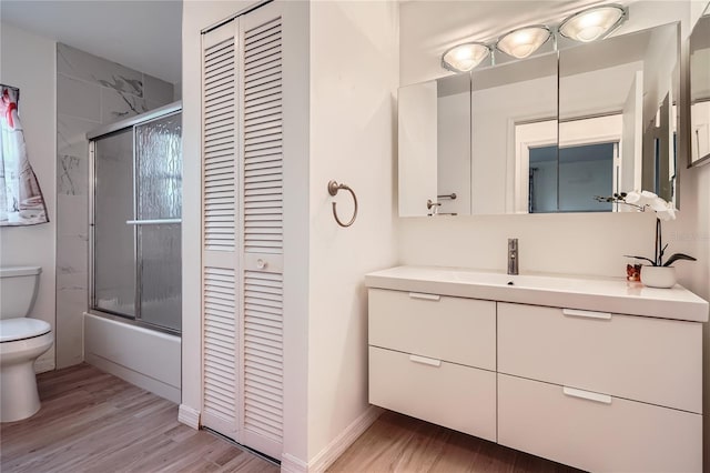 full bathroom with wood-type flooring, toilet, vanity, and enclosed tub / shower combo