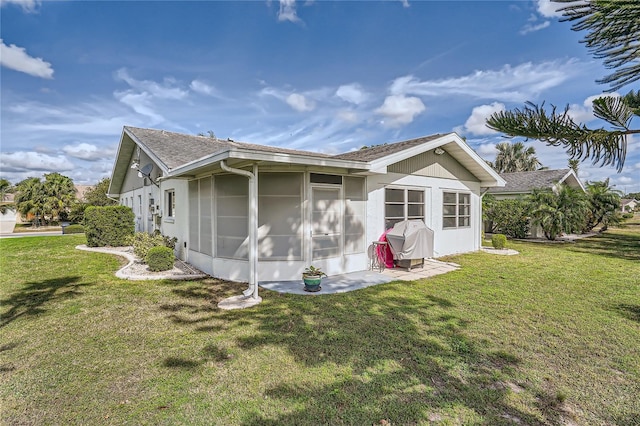 rear view of house featuring a lawn and a sunroom