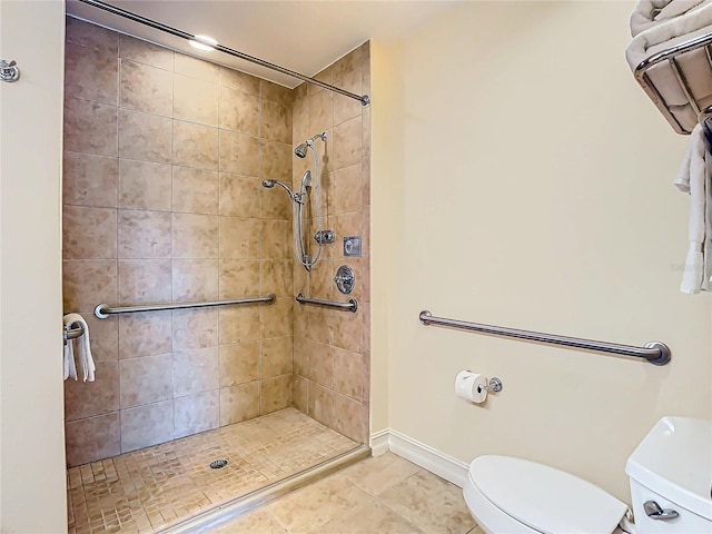 bathroom featuring tile patterned floors, toilet, and tiled shower