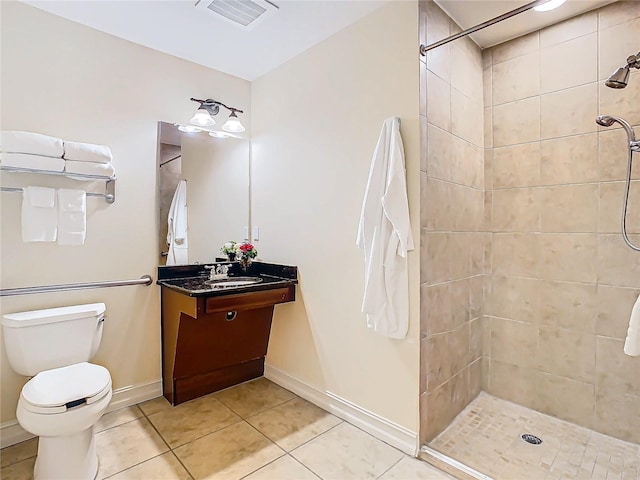 bathroom featuring vanity, tile patterned flooring, toilet, and a tile shower