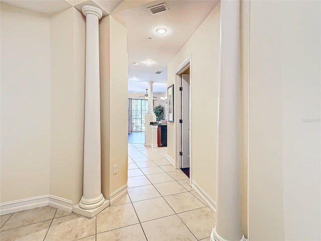 hall featuring light tile patterned flooring and decorative columns