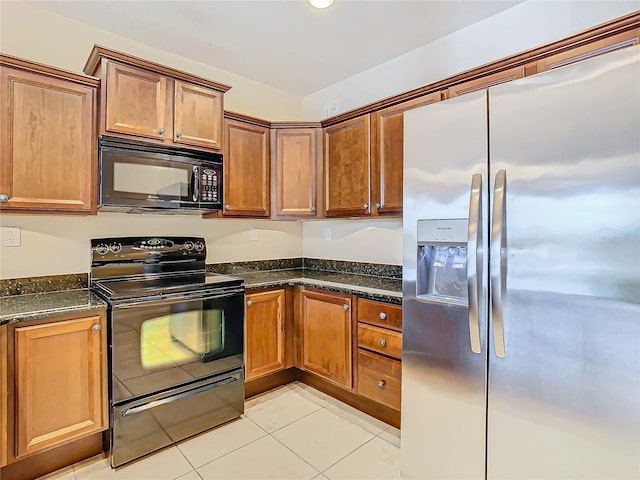 kitchen featuring black appliances, dark stone countertops, and light tile patterned floors