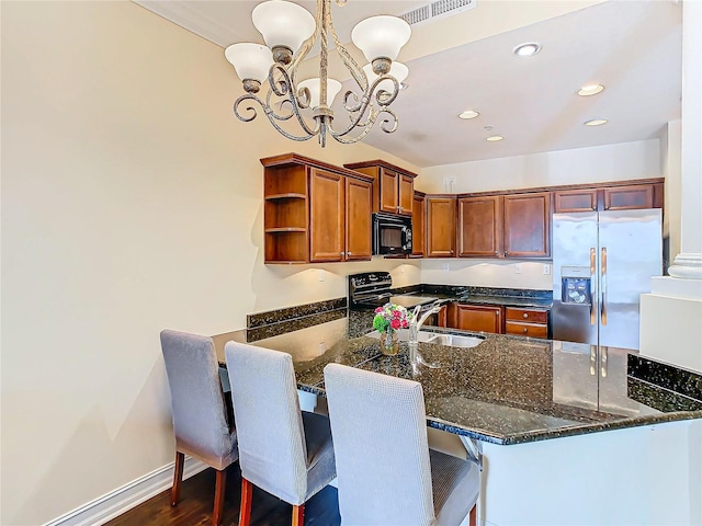 kitchen with a breakfast bar, kitchen peninsula, black appliances, dark stone countertops, and decorative light fixtures