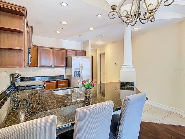 kitchen featuring dark stone counters, decorative light fixtures, stove, stainless steel refrigerator with ice dispenser, and light hardwood / wood-style floors