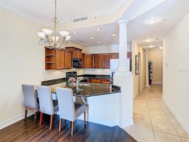 kitchen with ornamental molding, range, ornate columns, a notable chandelier, and kitchen peninsula