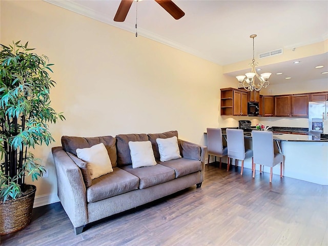 living room featuring ceiling fan with notable chandelier, dark hardwood / wood-style flooring, and crown molding