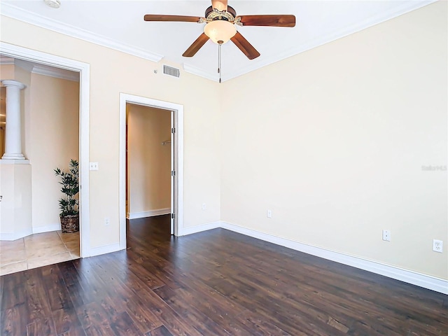 spare room featuring dark wood-type flooring, ceiling fan, ornate columns, and ornamental molding