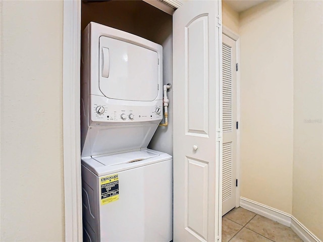 laundry room with light tile patterned flooring and stacked washer and dryer