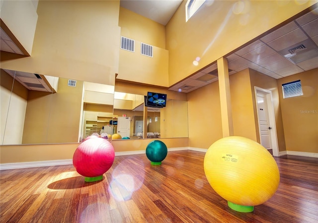 workout room with hardwood / wood-style flooring and a high ceiling