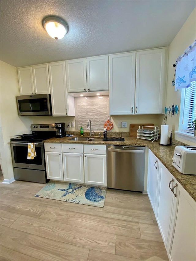 kitchen featuring white cabinets, sink, appliances with stainless steel finishes, and a textured ceiling